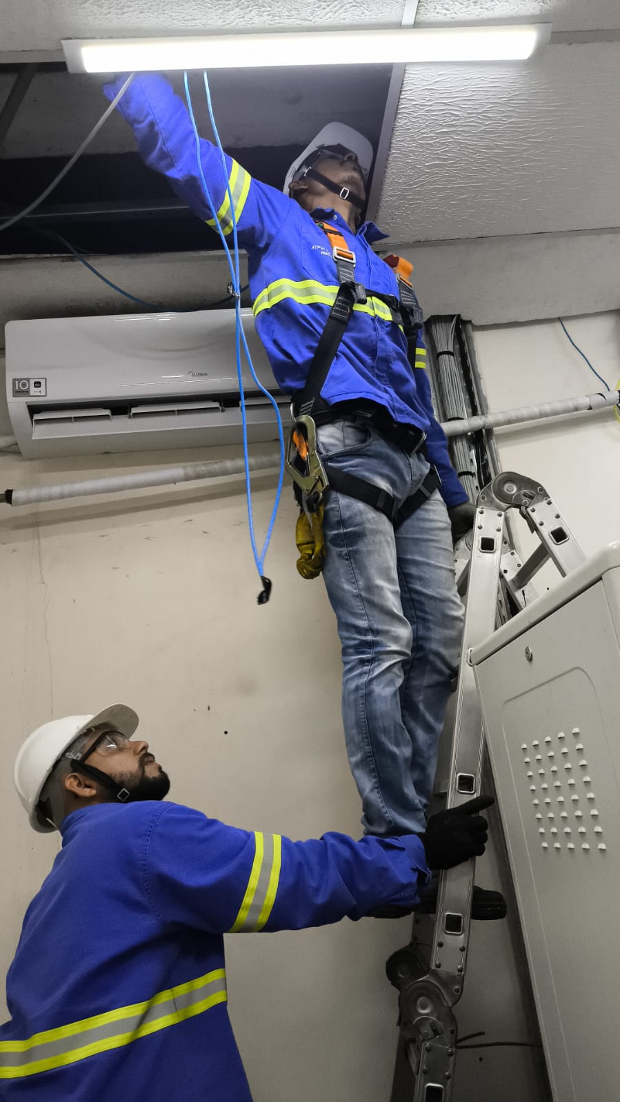 Técnicos UP Tech instalando cabeamento em altura com harness de segurança