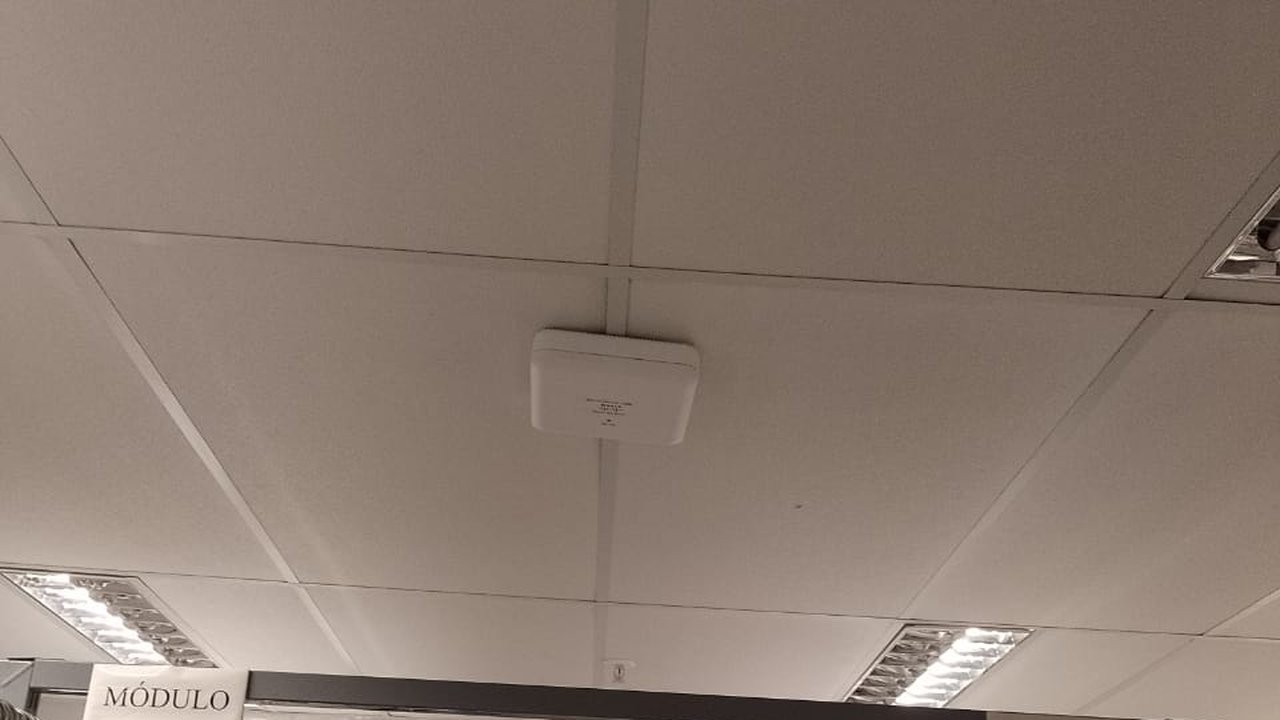 Access point instalado no teto de ambiente comercial — WiFi corporativo UP Tech